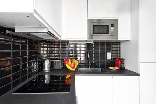 une cuisine avec un évier et un micro-ondes dans l'établissement 866 Suite Lilas - Superbe appartement, à Montreuil