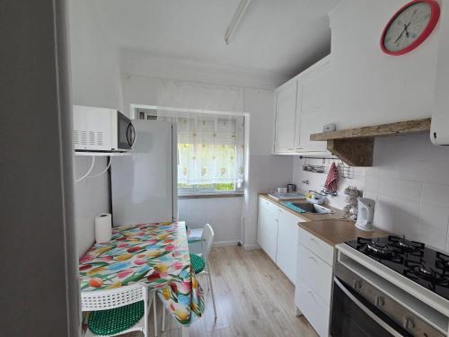 a kitchen with white cabinets and a table and a clock at Peaceful Stay - Lisbon in Amadora