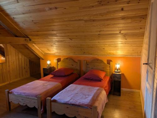 deux lits dans une chambre aux murs en bois dans l'établissement La Grange, à Le Noyer