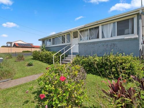 a house with some flowers in the yard at Sandy Toes in Sawtell