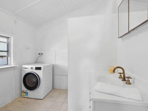 a white bathroom with a washing machine and a sink at Sandy Toes in Sawtell