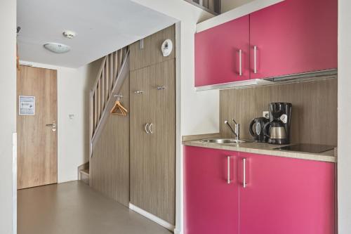 a kitchen with pink cabinets and a sink at Appart'hôtel Odalys City - Dijon Centre Les Cordeliers in Dijon