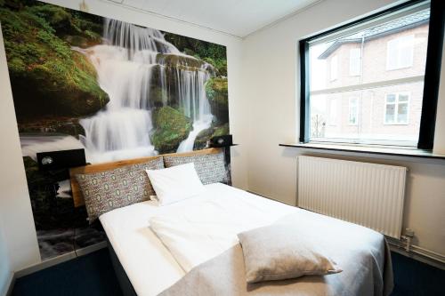 a bedroom with a bed with a waterfall painting on the wall at Hotel Vildbjerg in Vildbjerg