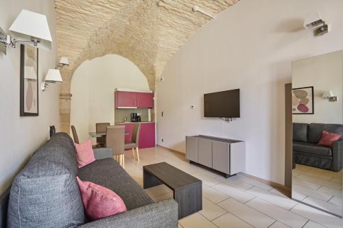 a living room with a couch and a tv at Appart'hôtel Odalys City - Dijon Centre Les Cordeliers in Dijon