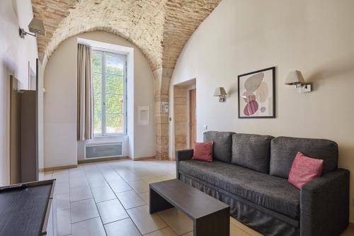 a living room with a couch and a table at Appart'hôtel Odalys City - Dijon Centre Les Cordeliers in Dijon