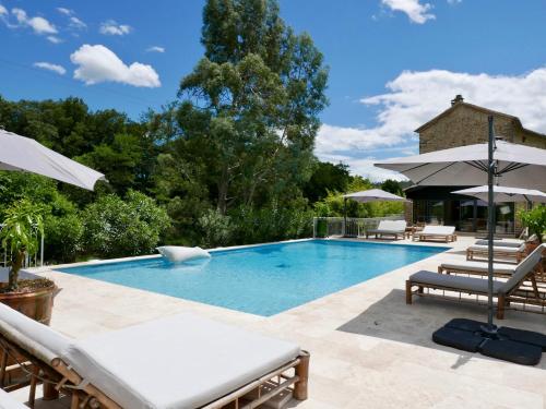 une piscine avec chaises longues et parasols dans l'établissement Le Moulin de l'Auzonnet, à Les Mages
