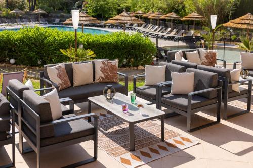 a group of chairs and tables next to a pool at Hotel Club Le Capet in Sainte-Maxime