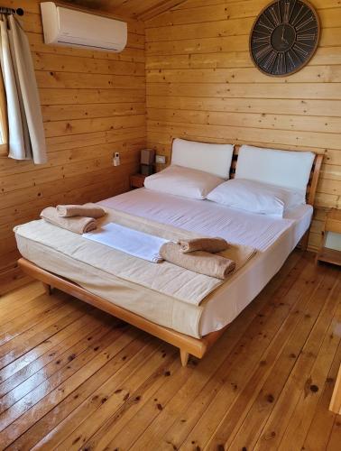 a bed in a wooden room with a clock on the wall at Linda House Corfu in Gastouri