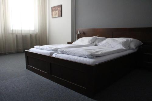 a bed with a wooden headboard in a bedroom at Hotel Palác in Olomouc
