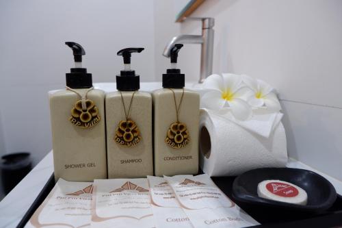 three bottles of soap sitting on a counter next to a sink at Phi Phi Villa Resort in Phi Phi Don