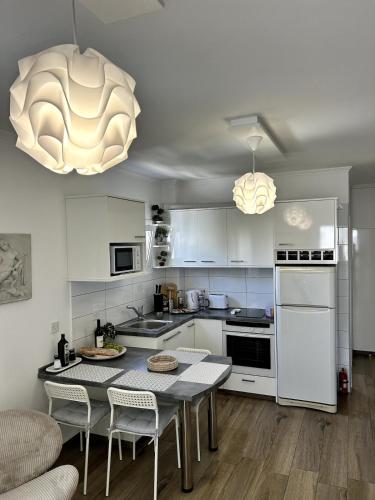 a kitchen with white cabinets and a table with chairs at Sunlit Serenity in Paphos in Paphos