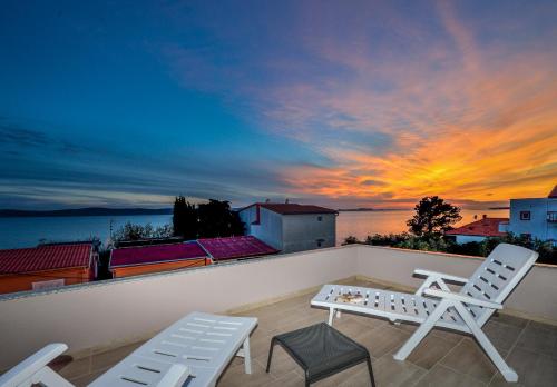 a balcony with chairs and a table and a sunset at Apartment Stipan in Bibinje