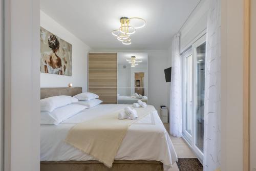 a white bedroom with two beds and a chandelier at Penthouse Alure in Split