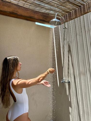 a woman in a white bikini playing in a shower at Ammoo in Amoopi