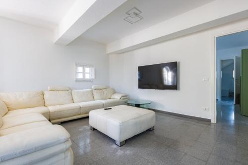 a white living room with a couch and a tv at Villa Tina in Patti