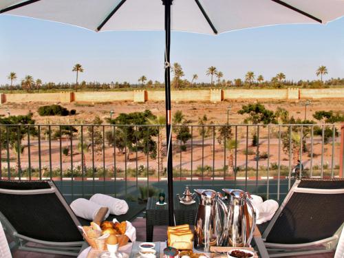a table with an umbrella and a view of a field at Rawabi Hotel Marrakech & Spa in Marrakech