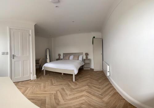 a bedroom with a white bed and a wooden floor at Guest Rooms at Walton Hall Farm in Stanford le Hope