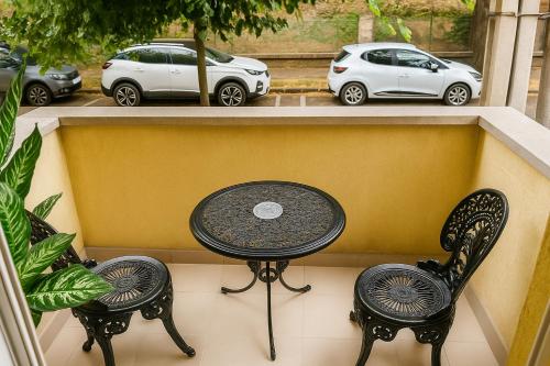 a table and two chairs on a balcony with parked cars at Royal Wellness Apartman in Hévíz