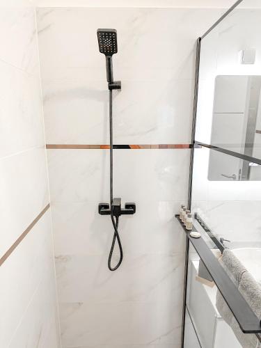 a shower in a white bathroom with a black shower head at Royal Wellness Apartman in Hévíz