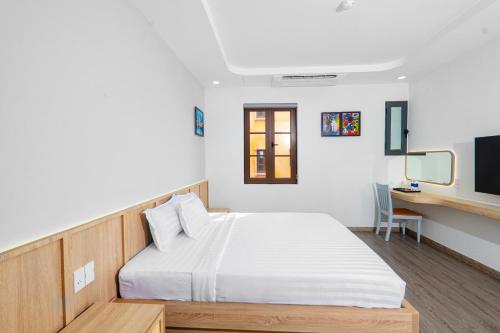 a bedroom with a white bed and a desk at Jana Hotel & Apartment - Firework & Aquatopia Water Park in Phu Quoc