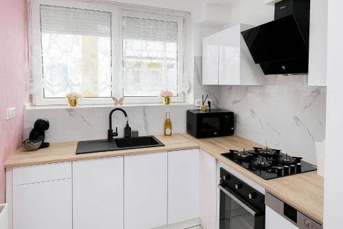 a white kitchen with a sink and a stove at Royal Wellness Apartman in Hévíz