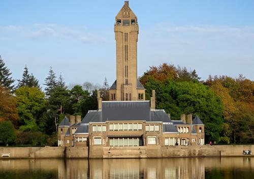 a building with a clock tower in the middle of the water at 6 Guest 3 BDR - Cozy Chalets VIP - Veluwe ijsvogel in Voorthuizen
