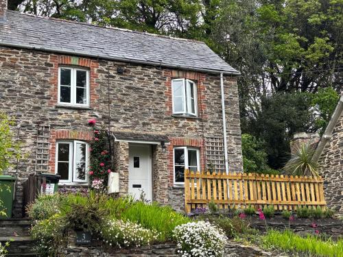 a small brick house with a fence and flowers at Idyllic Cottage near Padstow in Little Petherick
