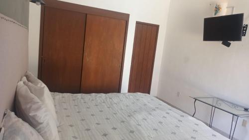 a bedroom with a bed with a wooden closet and a television at Bonanza Garden Suite s in Cuernavaca