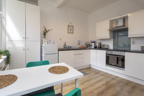 a kitchen with white cabinets and a table and chairs at Glenmore Lodge in Belfast