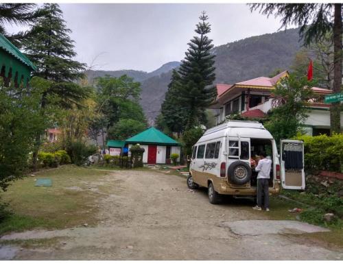 a man standing next to a van parked in a driveway at Hotel महिमा रेसॉर्ट in Uttarkāshi
