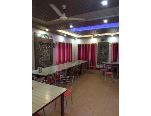 a row of tables and chairs in a room with red curtains at Hotel महिमा रेसॉर्ट in Uttarkāshi