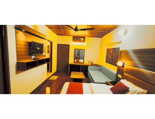 a living room with a couch and a television at Hotel महिमा रेसॉर्ट in Uttarkāshi
