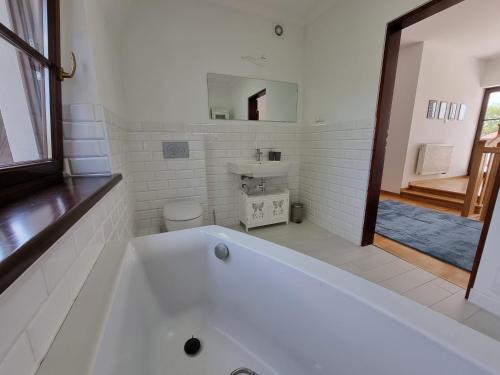 un bagno bianco con vasca e lavandino di visit baltic - Dom wakacyjny Simona Ferienhaus Szkolna a Świnoujście