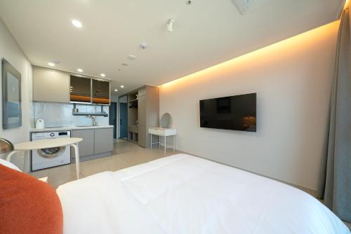 a bedroom with a white bed and a tv on a wall at DIAMER Hotel Sokcho by AankStay in Yangyang
