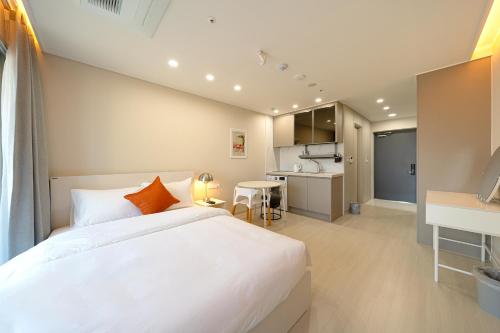 a bedroom with a large white bed and a kitchen at DIAMER Hotel Sokcho by AankStay in Yangyang