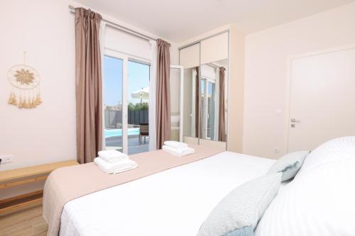 a bedroom with two beds and a large window at Poet Villa in Agios Georgios