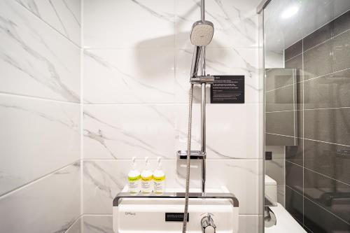 a white bathroom with a shower with three bottles at DIAMER Hotel Sokcho by AankStay in Yangyang