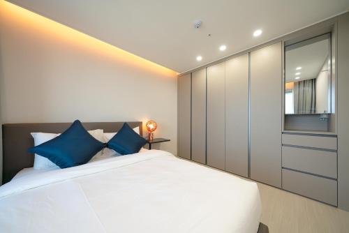 a bedroom with a large white bed with blue pillows at DIAMER Hotel Sokcho by AankStay in Yangyang