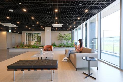 a woman sitting on a couch in a lobby at DIAMER Hotel Sokcho by AankStay in Yangyang