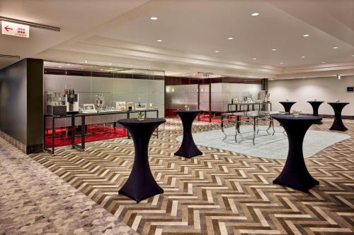 a hotel lobby with black stools and a bar at Sheraton Duesseldorf Airport Hotel in Düsseldorf