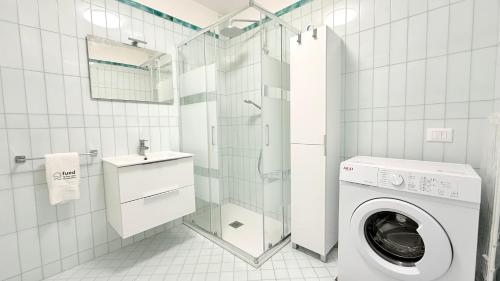 a white tiled bathroom with a washing machine at SE190 - Senigallia, bilocale ristrutturato con aria condizionata in Senigallia
