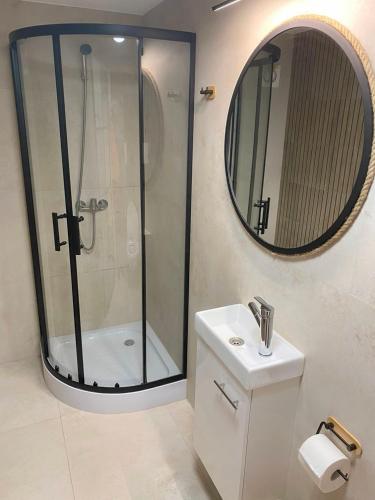 a bathroom with a shower and a sink and a mirror at MOJA OSTOJA APARTAMENTY & KAJAKI - Spływy Kajakowe Rzeką Krutynią in Ruciane-Nida
