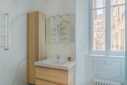 une salle de bain blanche avec un lavabo et une fenêtre dans l'établissement Paris Palais des Congrès Residence, à Neuilly-sur-Seine