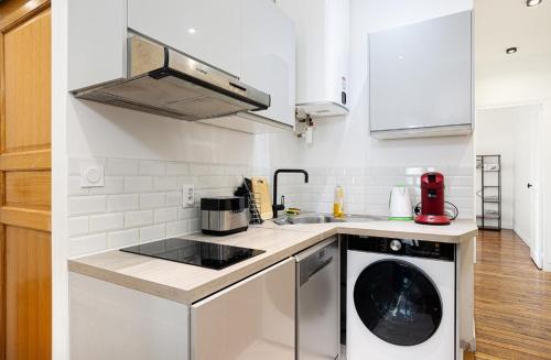 a white kitchen with a washing machine in it at Beautiful renovated apartment near La Défense Arena in Courbevoie