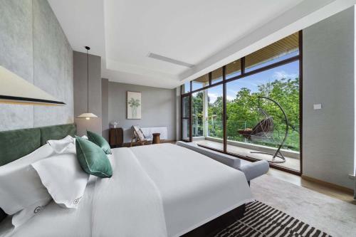 una camera da letto con un grande letto bianco e una grande finestra di Chengdu Flowing Strings peninsula boutique hotel-Near the Sichuan Cuisine Museum a Pi