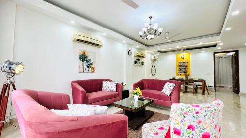 a living room with two pink couches and a table at BluO 3BHK Safdarjung Enclave, Lift & Terrace Garden in New Delhi