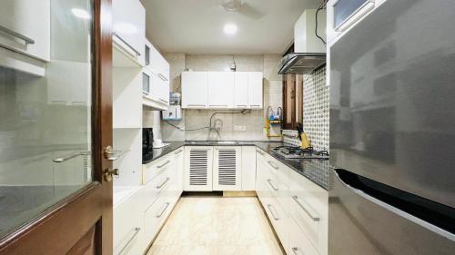 a kitchen with white cabinets and a door open at BluO 3BHK Safdarjung Enclave, Lift & Terrace Garden in New Delhi