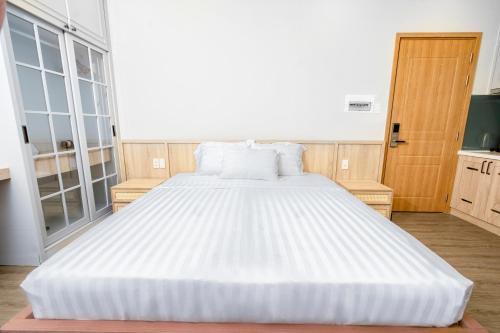 a large white bed in a room with windows at Jana Hotel & Apartment - Firework & Aquatopia Water Park in Phu Quoc