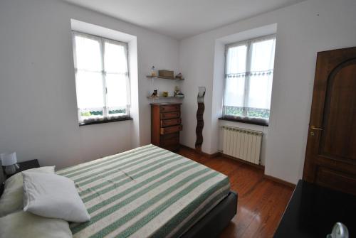 a bedroom with a bed and two windows at Casa Anna in Uscio