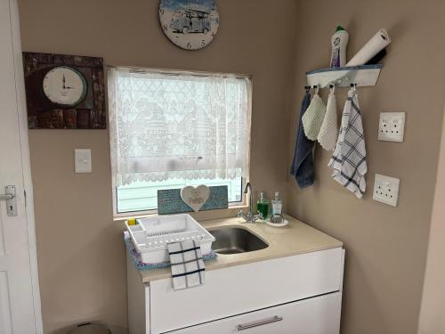 a small kitchen with a sink and a window at Knight & Sunshine Luxury Flatlet in Kleinbaai
